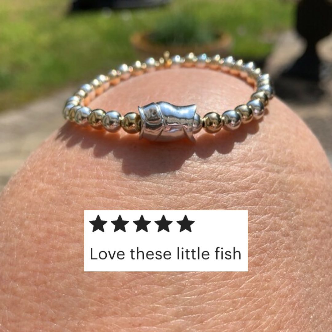Picture of a silver fish bead on a bracelet of beads