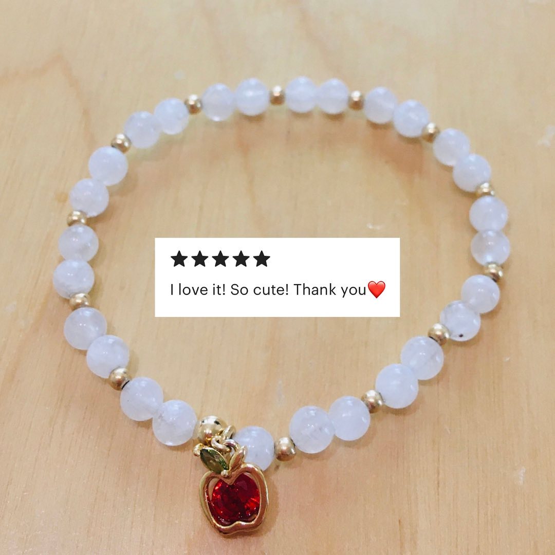 Picture of an apple charm on a beaded bracelet with a review saying, "I love it! So cute! Thank you."