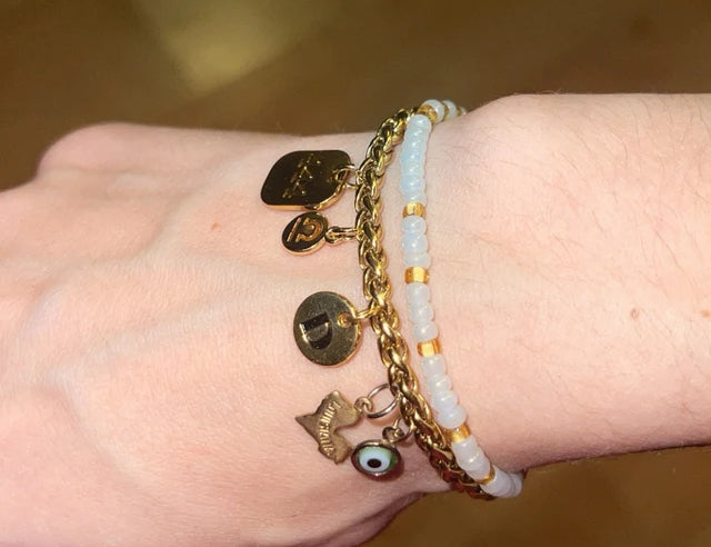 Picture of a bracelet with 5 unique charms (an eye, a heart, a 'D' initial, and two other minimal charms) on a woman's wrist